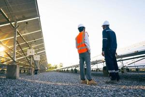 ingenieros con inversores caminan para verificar el funcionamiento de la granja solar, sistemas de paneles solares, energía alternativa para conservar el mundo es energía, idea de módulo fotovoltaico para la producción de energía limpia foto