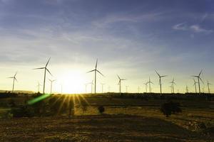 la granja de turbinas eólicas es una fuente de electricidad alternativa, concepto de recursos sostenibles, hermosa luz solar naranja en verano con turbinas de generadores de viento en segundo plano, concepto de energía renovable foto