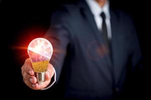 Businessman holds a light bulb with a picture of sunlight and a solar cell inside the light bulb.