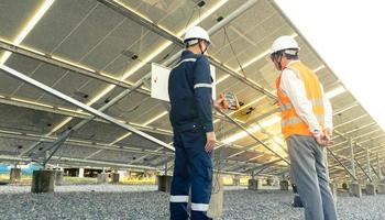 ingenieros con inversores caminan para verificar el funcionamiento de la granja solar, sistemas de paneles solares, energía alternativa para conservar el mundo es energía, idea de módulo fotovoltaico para la producción de energía limpia foto