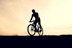 siluetas de bicicletas de montaña y ciclistas por la noche felizmente. concepto de viaje y fitness foto