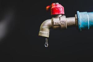 concepto de crisis de escasez de agua dulce debido a cambios ambientales. grifo de agua sin agua corriente sobre un fondo negro hay un espacio de copia. foto