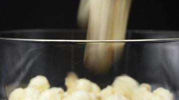 häll popcorn i ett roterande glas på en svart bakgrund. video