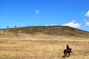 a rider rides a horse through a hilly valley photo