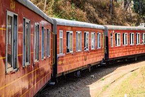 Toy Train moving on mountain slopes, beautiful view, one side mountain, one side valley moving on railway to the hill, among green natural forest. Toy train from Kalka to Shimla in India photo