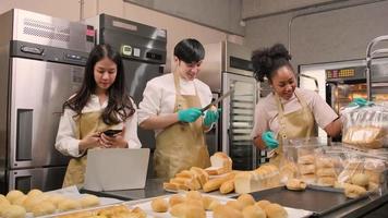 Three young friends and startup partners of bread dough and pastry foods busy with homemade baking jobs while cooking orders online, packing, and delivering on bakery shop, small business entrepreneur video