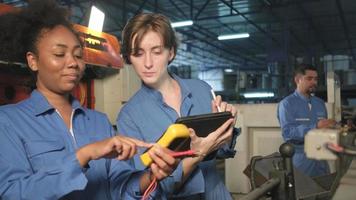duas trabalhadoras engenheiras profissionais em uniformes de segurança trabalham inspecionando a corrente de tensão das máquinas, verificando e mantendo na fábrica de fabricação, ocupações de serviço do sistema elétrico. video