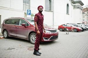 Portrait of African American military man in red uniform and beret near car. photo