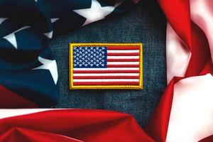 feliz día de la independencia 4 de julio. parche textil de la bandera americana en una chaqueta vaquera y bandera americana foto