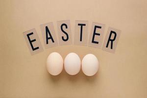 Easter eggs on pastel brown background with lettering. Top view. Flat lay. Minimal concept photo