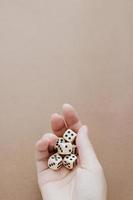 Female hand holds white gaming dice on brown background. Concept with copy space for games, game board, role playing game, risk, chance, good luck or gambling. Toned image top view. Close-up photo