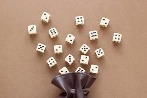 Set of gaming dice rolled out of leather bag on brown background. Concept with copy space for games, game board, role playing game, dnd,  risk, chance, good luck or gambling. Toned image top view photo