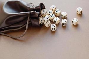 Set of gaming dice rolled out of leather bag on brown background. Concept with copy space for games, game board, role playing game, dnd,  risk, chance, good luck or gambling. Toned image top view photo