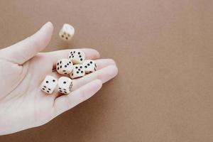 Female hand holds white gaming dice on brown background. Concept with copy space for games, game board, role playing game, risk, chance, good luck or gambling. Toned image top view. Close-up photo