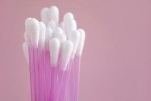 Close up of cotton buds on pink background. Cosmetic concept with copy space. Medicine and personal hygiene photo