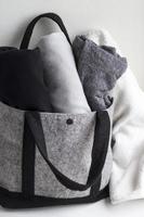 Close-up rolled clothes in woolen gray bag on white background. Black, grey and white textiles. Monochrome concept. photo