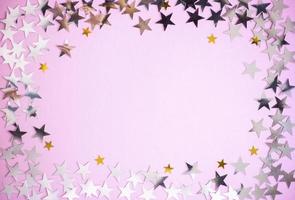 marco de estrellas brillantes plateadas y doradas sobre fondo rosa. concepto de decoración con espacio de copia para diseño, exhibición, vacaciones foto