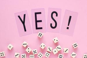Gaming dice with word YES on pink background. Concept for games, game board, presentation, banners or web. Top view. Close-up photo