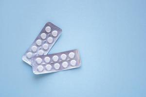 Two packing of white tablets with copy space on blue background. Medical concept treatment of diseases, sale of tablets, tablets in blister pack. photo