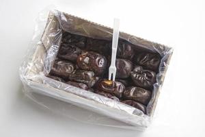 Dried date palm fruits in box on white background. Pile of fresh date fruits for dietary nutrition. Top view photo