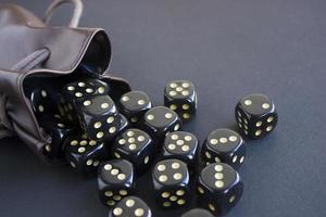 juego de primeros planos de dados de juego sacados de una bolsa de cuero sobre fondo oscuro. concepto con espacio de copia para juegos foto