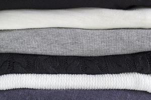 Close-up stack of folded cozy clothes. Black, grey and white textiles clothing. Monochrome fabric. photo