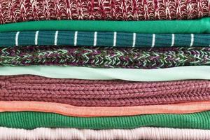 Close-up stack of folded colorful clothes. Background of different cozy clothes. Colorful fabric