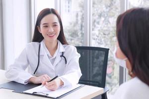 Asian professional woman doctor suggests healthcare solution to her patient elderly in examination room at hospital. photo