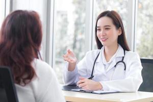 Asian professional  woman doctor suggests healthcare solution to her patient elderly in examination room at hospital. photo