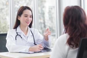 Asian professional  woman doctor suggests healthcare solution to her patient elderly in examination room at hospital. photo