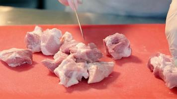 preparación y procesamiento de carne cruda. el cocinero corta pequeños trozos de carne. video