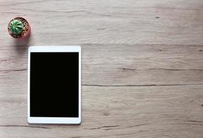 Tablet and cactus Put on a wooden table with copy space. photo