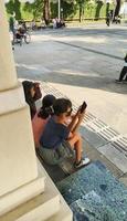 sukoharjo - 23 de mayo de 2022 - un niño pequeño sentado en el borde de la casa jugando con su teléfono celular foto
