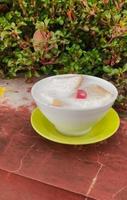 Wedang Asle food served in a bowl filled with milk mixed with sticky rice and a few small slices of white bread photo