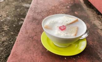 Wedang Asle food served in a bowl filled with milk mixed with sticky rice and a few small slices of white bread photo