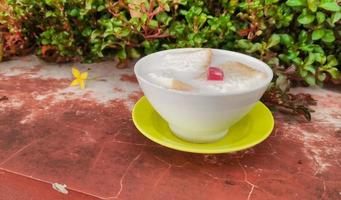 wedang asle comida servida en un tazón lleno de leche mezclada con arroz pegajoso y unas rebanadas pequeñas de pan blanco foto