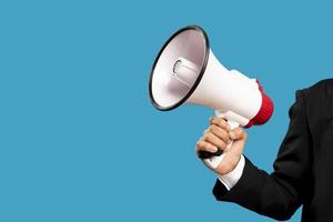 Announcement concept. Hand holds megaphone. Isolated on blue background. photo