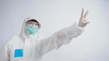 Doctor in PPE suit gesture make hand sign. Represent victory win over virus. photo