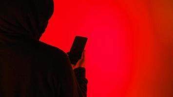 Anonymous hacker and face mask with smartphone in hand. photo