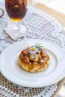 Homemade puff pastry deep fried donuts or cronuts in stack with sugar standing on white plate over table top with lace tablecloth. croissant and doughnut topping with macadamia nut and caramel sauce. photo