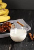 Banana, Dates Fruit, and Cinnamon Smoothie or Milkshake in a Glass on a Wooden Table with Grey Background photo