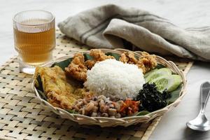 Nasi Campur Cumi Asin, White Rice with Sautee Salted Squid, Sambal, Egg, Kulit Ayam Crispy Chicken Skin, and Boiled Cassava Leaf. photo