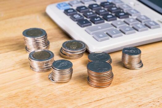 stack of coin with blurred calculator for blackground on wood table photo