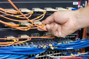 Hand of a man holding The network fiber optic cables to connect the port of a switch to connect internet network, concept Communication technology photo