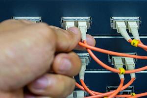 Hand of a man holding The network fiber optic cables to connect the port of a switch to connect internet network, concept Communication technology photo