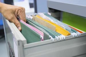 la mano del hombre busca documentos de archivos en un archivador en la oficina de trabajo, concepto de vida de la oficina de negocios. foto