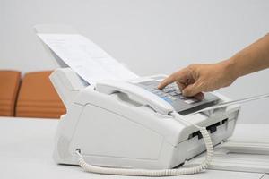 hand man está usando una máquina de fax en la oficina, equipo para transmisión de datos. foto