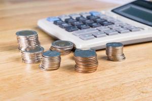 stack of coin with blurred calculator for blackground on wood table photo