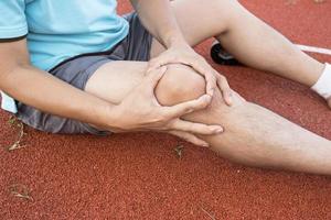 Problemas en las articulaciones de la rodilla del tendón en la pierna del hombre debido al ejercicio en el estadio. foto