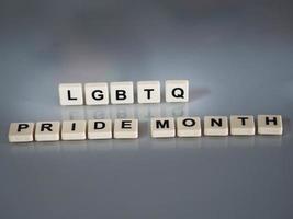 wording LGBTQ Pride month text in plastic English letters are stamped onto a plastic sheet reflected on the glass table photo